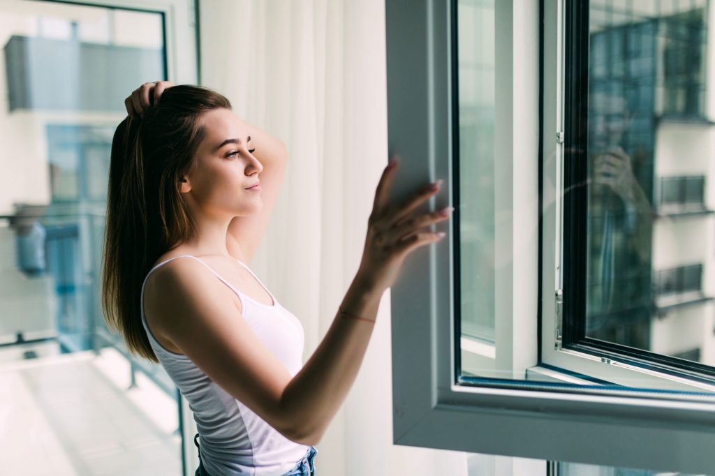 young-woman-opens-plastic-window-fresh-air-smiling-home